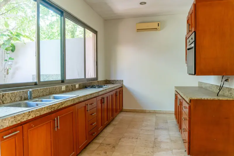 Cocina con gabinetes de madera y ventanal