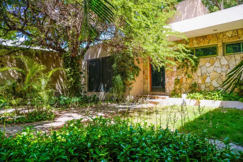 Jardín con vegetación tropical frente a la casa de piedra
