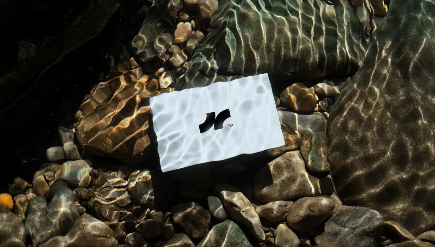 Tarjeta con el logotipo de Noyol bajo agua cristalina, sobre piedras de río