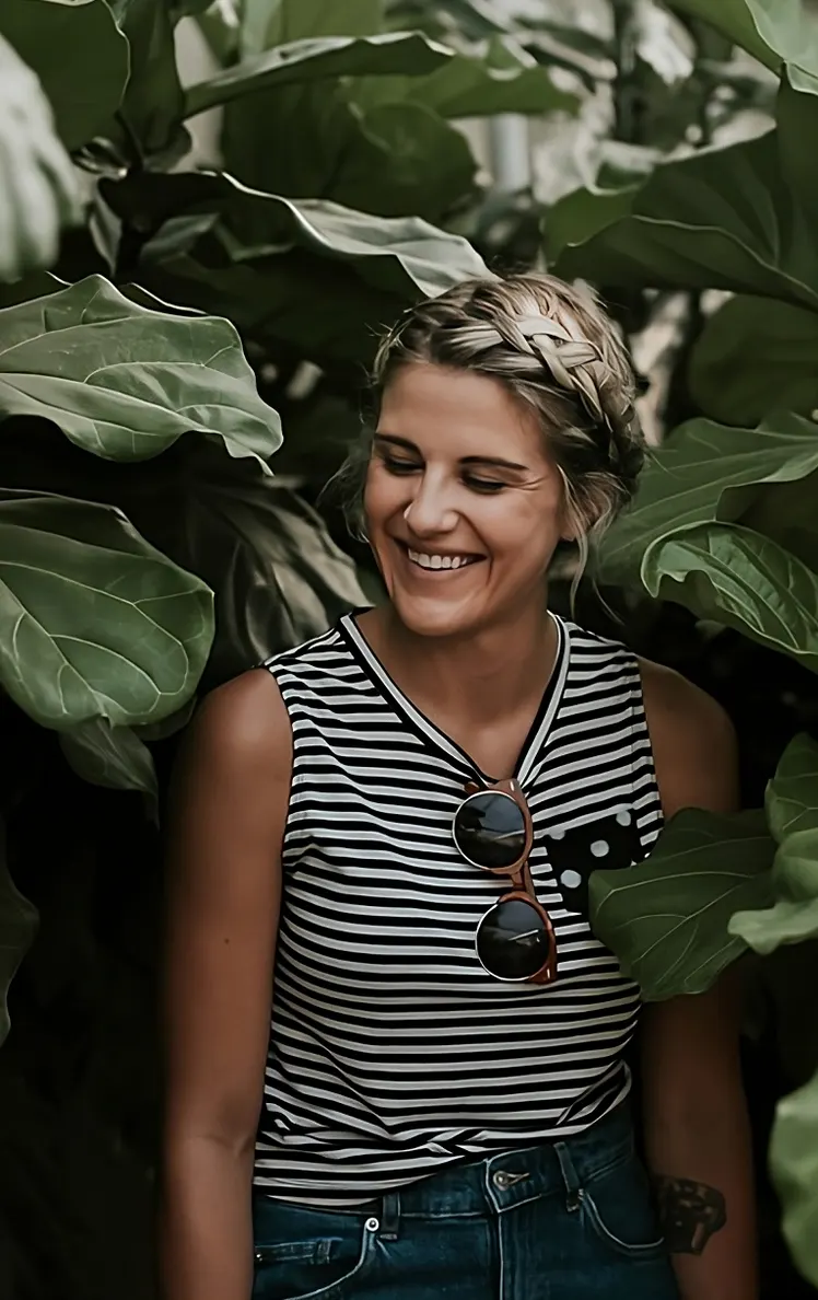 Clienta sonriente entre plantas de hojas grandes