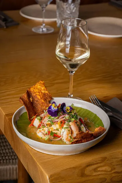 Ceviche de camarón servido junto a una copa de vino