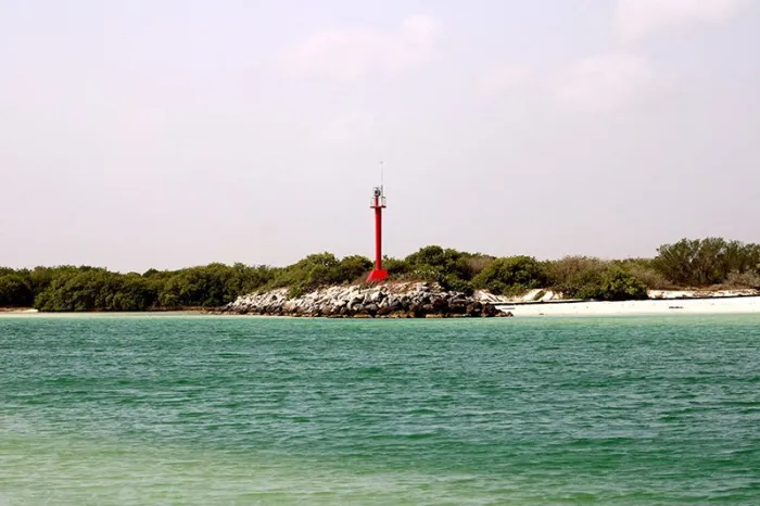 Faro rojo frente al mar turquesa
