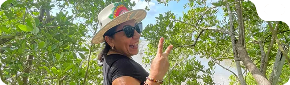 Clienta con sombrero hace la señal de paz entre los manglares